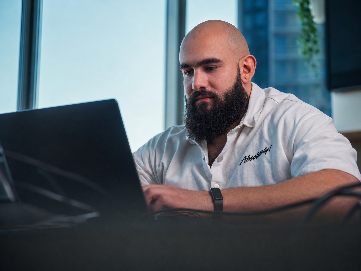 Founder working on a laptop with a WHOOP-style fitness band
